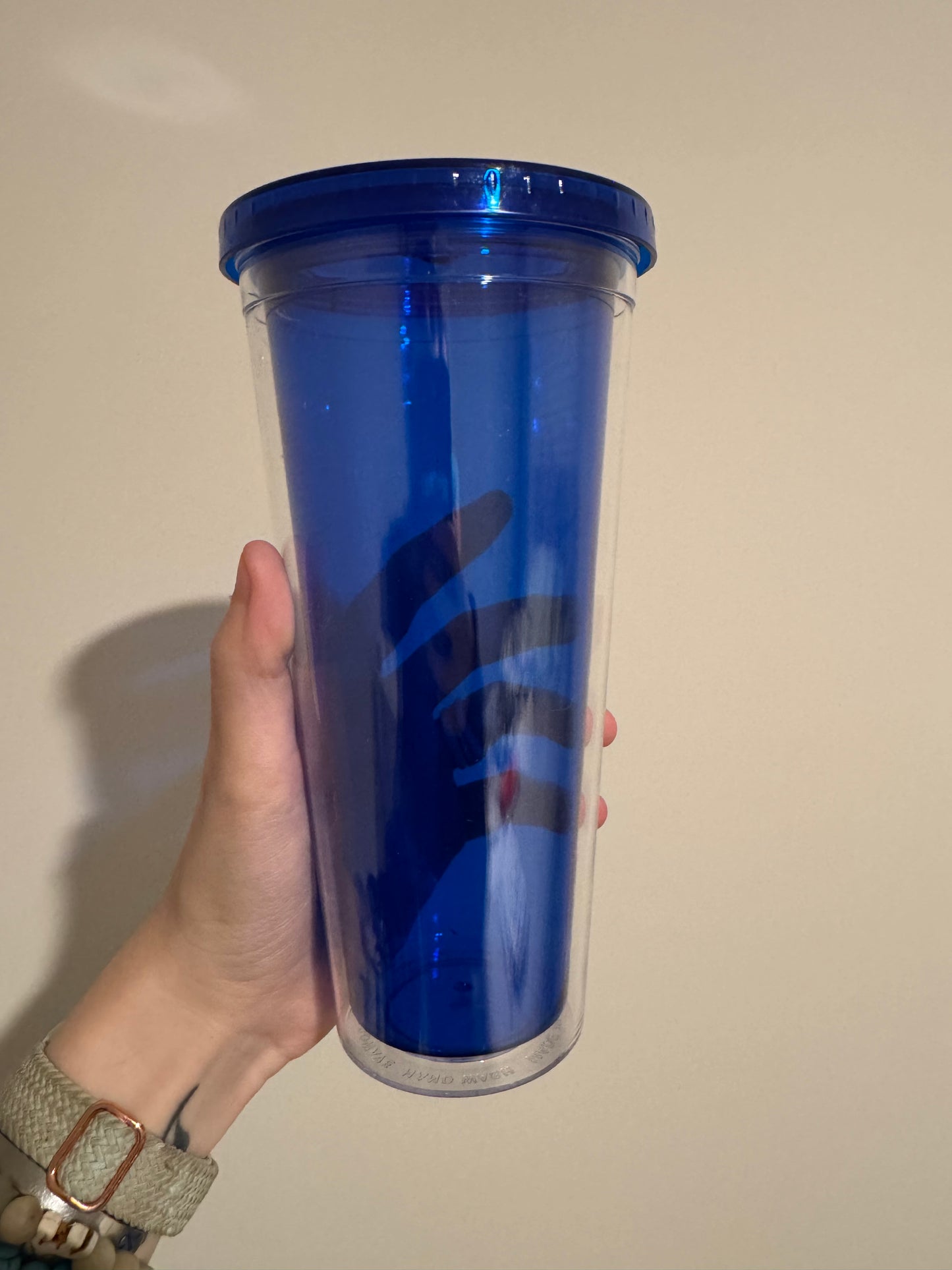 Hand holding a dark blue cylindrical container against a plain background