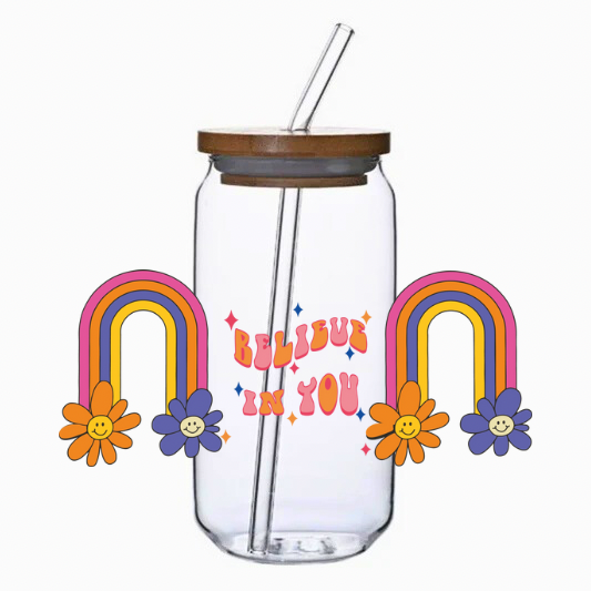 Clear glass tumbler with rainbow and flower designs, wooden lid, and metal straw on a white background.