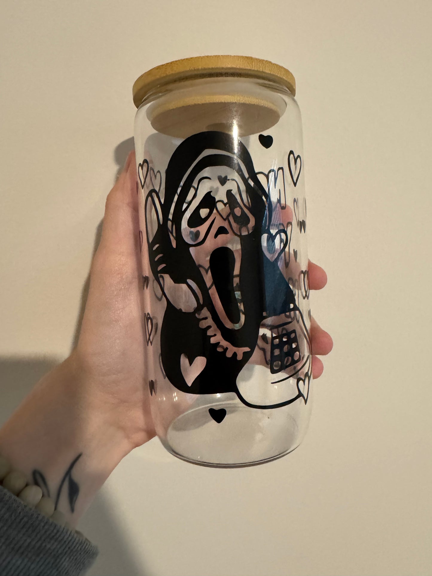 A hand holding a Ghost Face Vinyl Glass Cup 