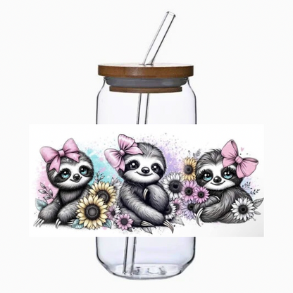 Glass tumbler with bamboo lid and straw featuring three sloths with pink bows and flowers on a white background.
