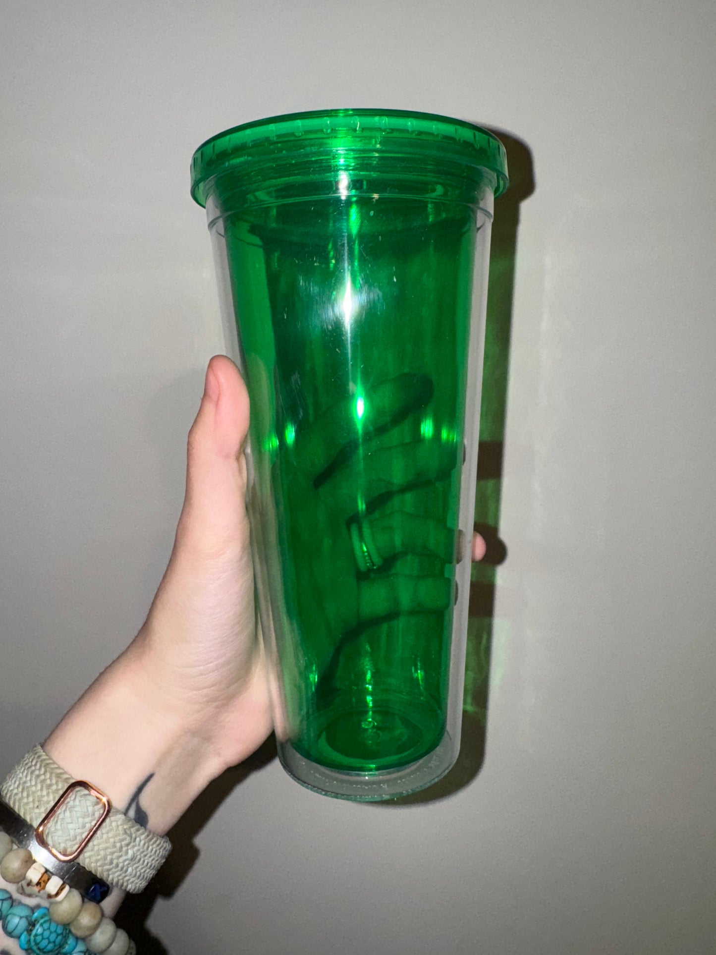 Hand holding a green cylindrical object against a plain background