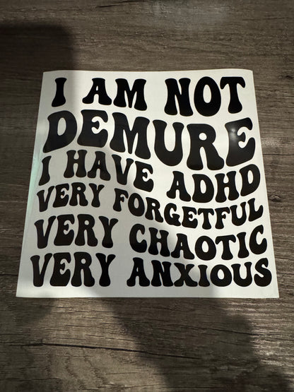 A black and white decorative sticker with text including phrases such as 'I AM NOT DEMURE' and 'I HAVE ADHD VERY FORGETFUL VERY CHAOTIC VERY ANXIOUS'.
