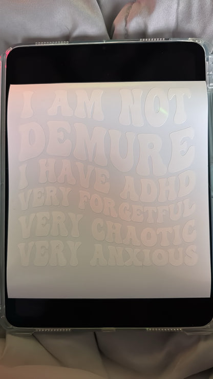A sheet of white vinyl with the text “I Am Not Demure I Have ADHD Very Forgetful Very Chaotic Very Anxious” 