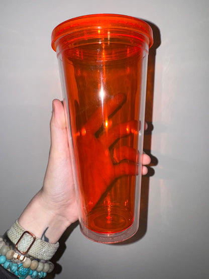 Hand holding an orange transparent container against a plain background