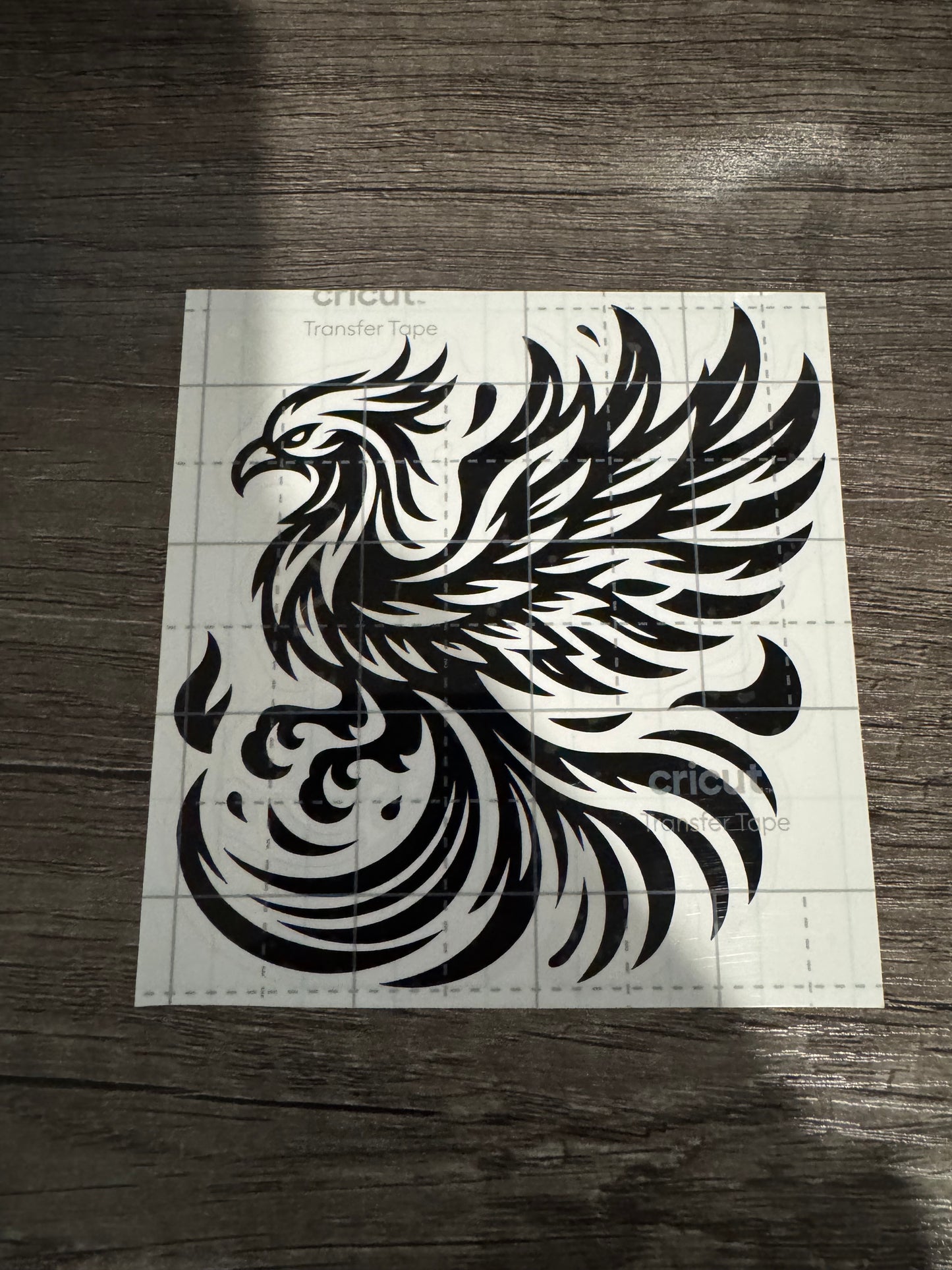 A black and white decal of a phoenix bird designed for use on a hoodie, cup, or other surface.