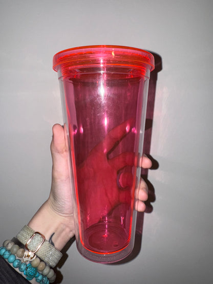 Hand holding a pink transparent container against a plain background