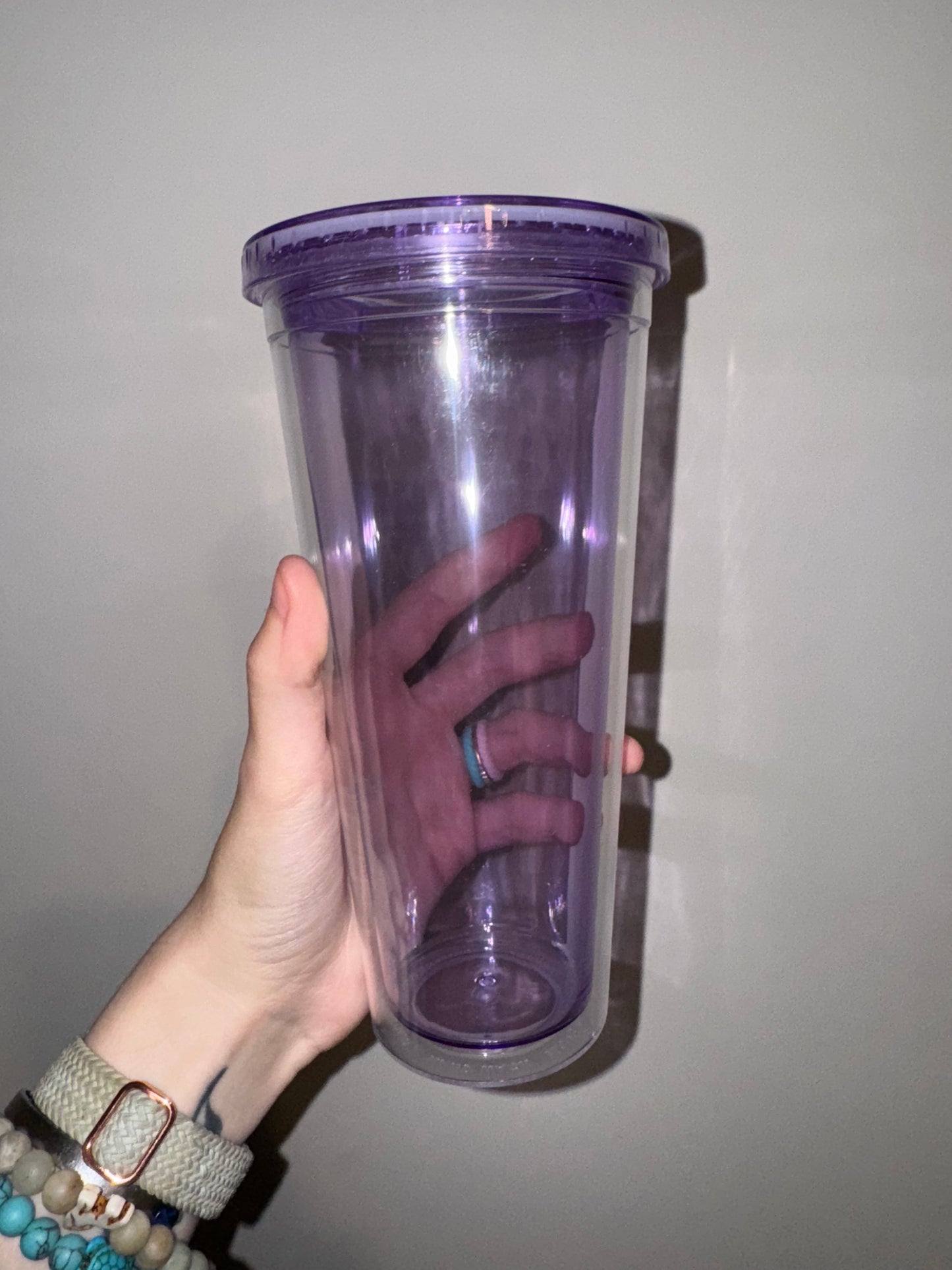 Hand holding a purple cylindrical container against a plain background