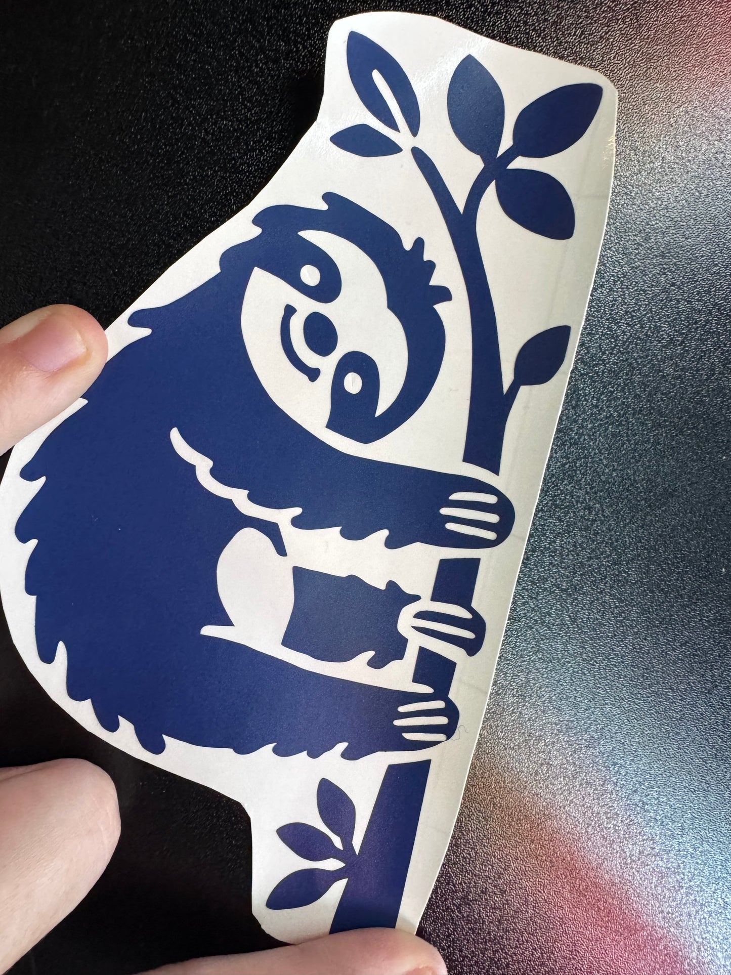 A sloth hanging onto a tree, navy blue vinyl decal 