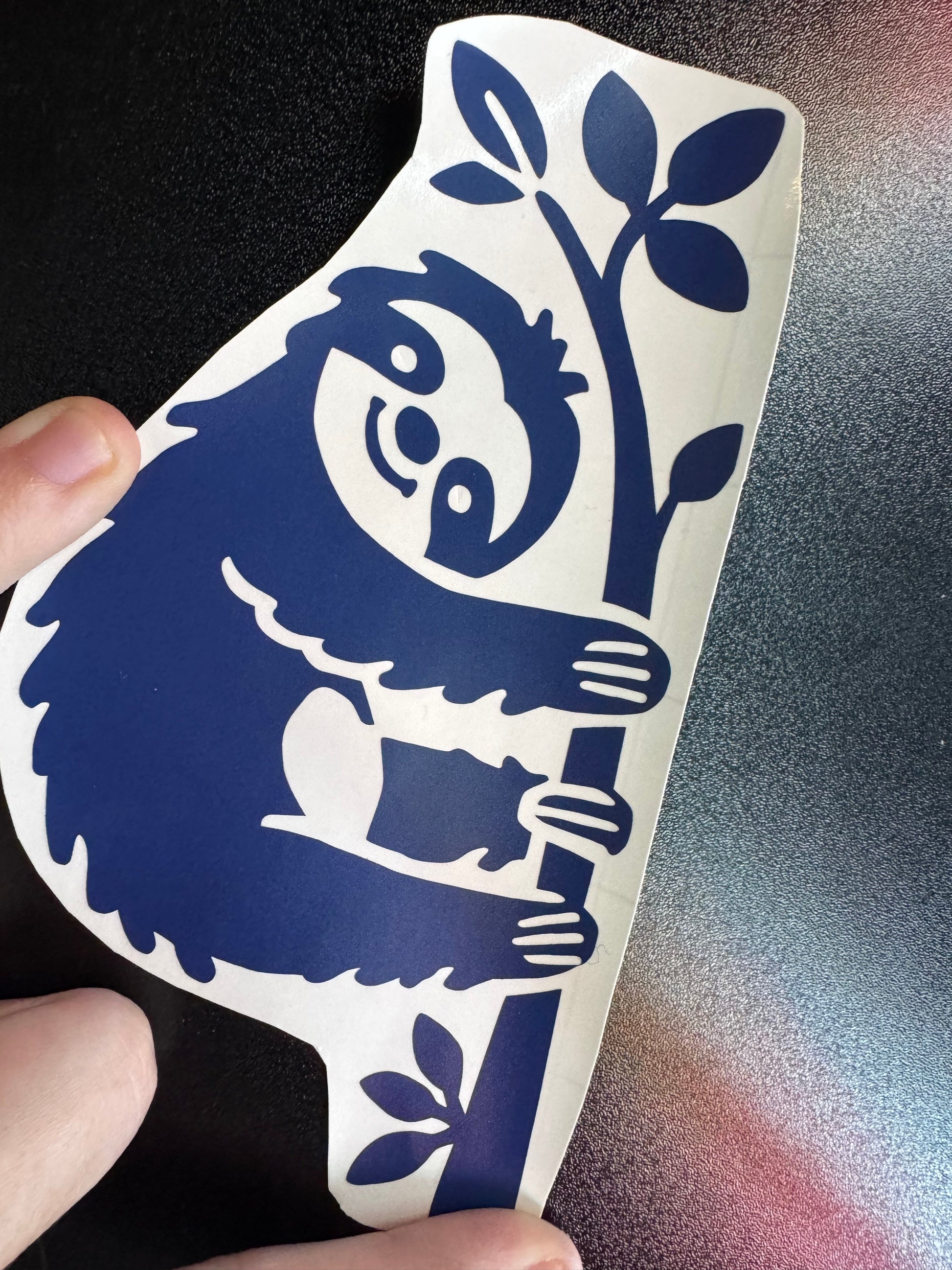 A sloth hanging onto a tree, navy blue vinyl decal 
